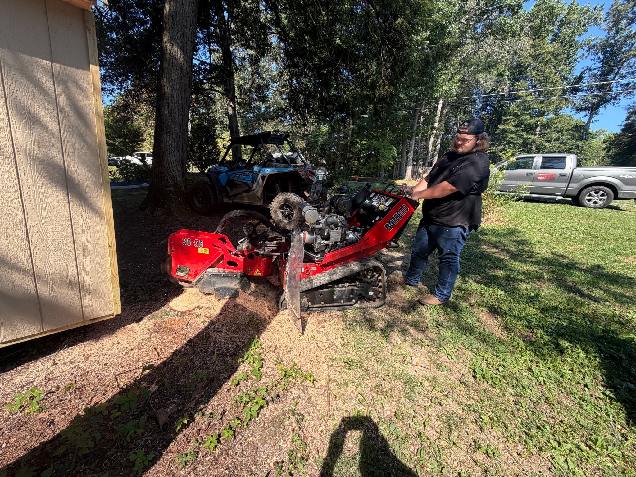 An operator grinding a stump with a tracked machine